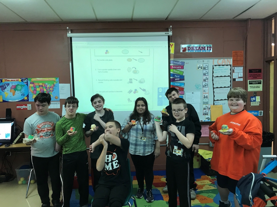 children in a classroom holding cupcakes